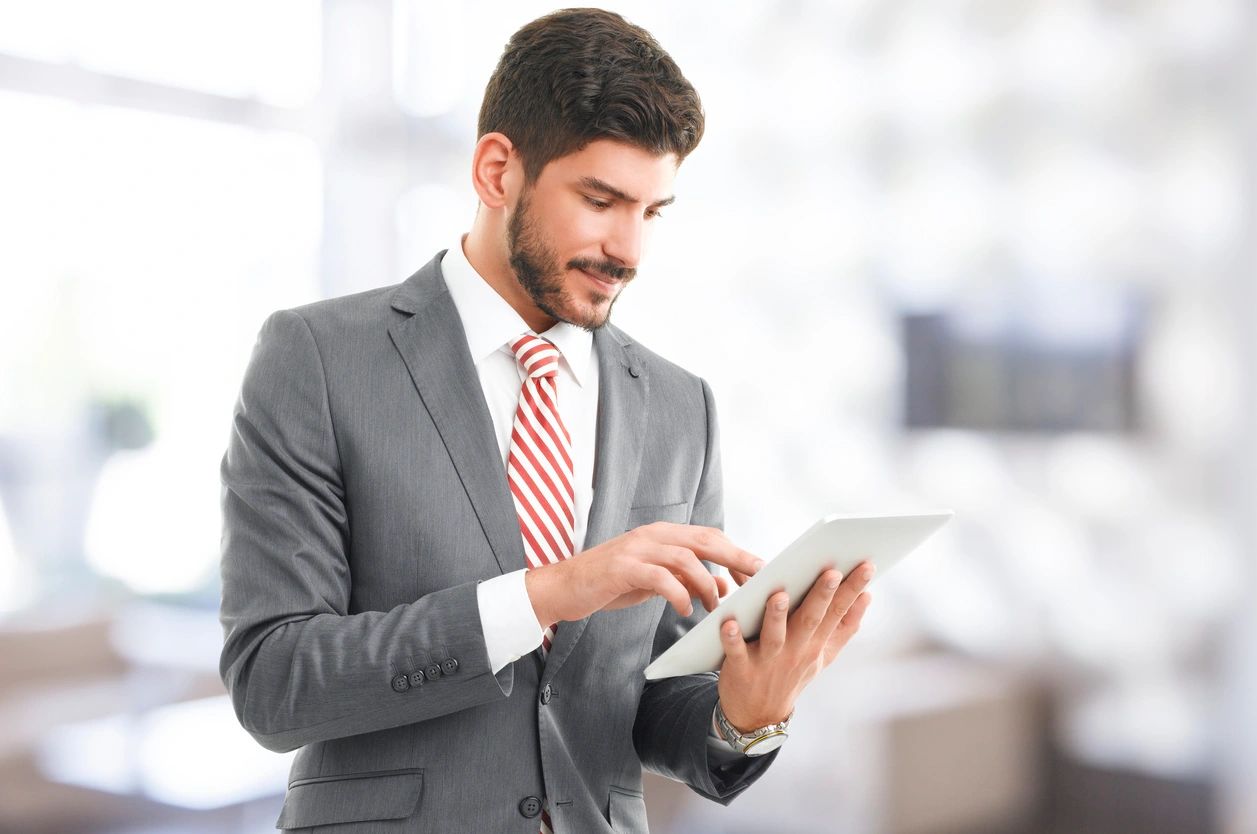 A man in a suit and tie holding a tablet.